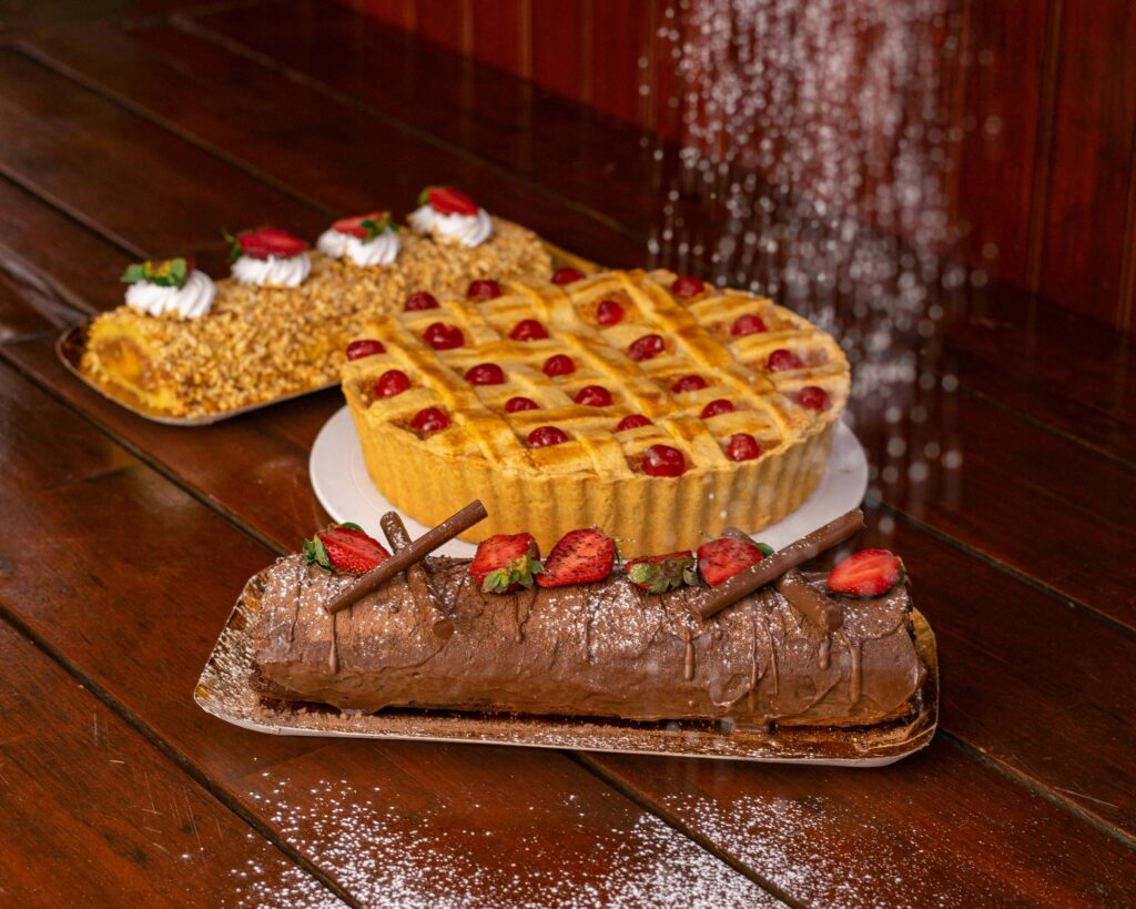 Delicious assortment of pies and cakes topped with fruit on a rustic wooden table.